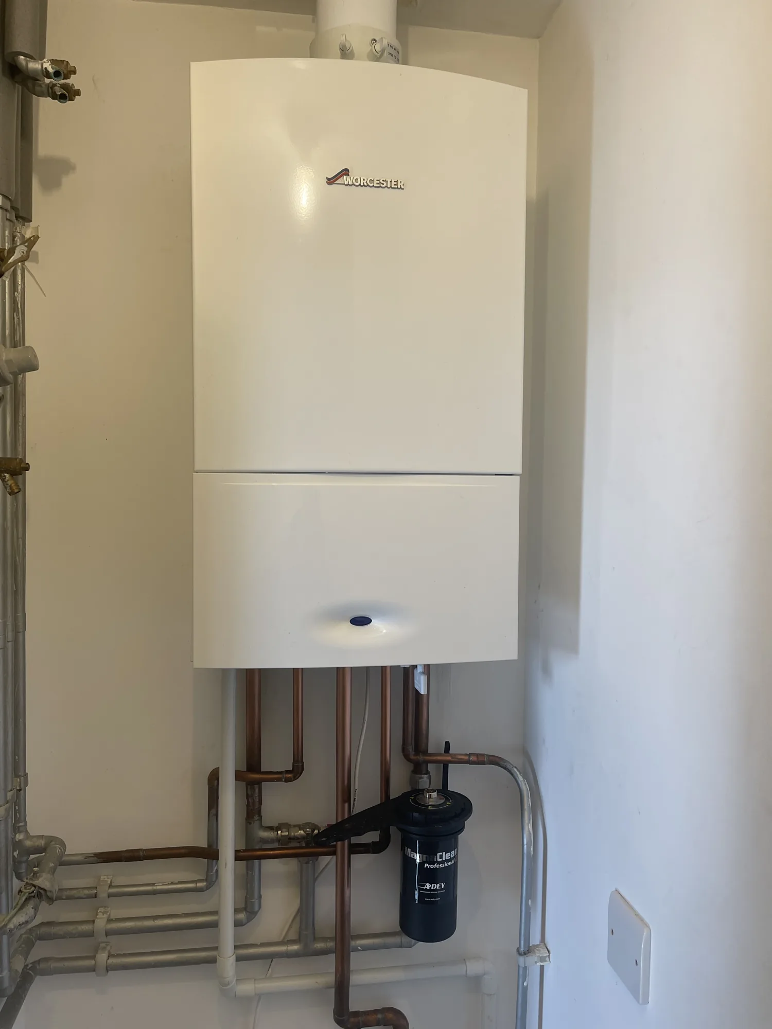 Completed boiler installation with tidy copper pipework and a system filter